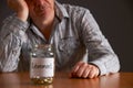 Depressed Man Looking At Empty Jar Labelled Retirement