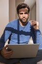 Depressed man sitting on floor using laptop Royalty Free Stock Photo