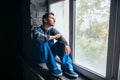 Depressed man sitting on the window sill, psycho