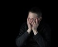 Depressed mature man holding his face with both hands while showing emotion of stress