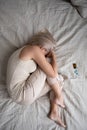 Depressed mature woman lying in bed with pills top view