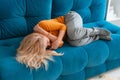 depressed mature woman lying sofa with her arms around herself, covering her head with hands, unhappy woman suffering