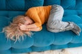 depressed mature woman lying sofa with her arms around herself, covering her head with hands, unhappy woman suffering