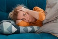 depressed mature woman lying sofa with her arms around herself, covering her head with hands, unhappy woman suffering