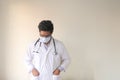 Depressed matured doctor standing against a wall looking down