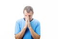 Depressed middle aged man praying over white background. Middle aged man praying for help with a desperate look over white