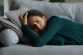 Depressed millennial latina female lie on sofa without sleep