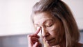 Depressed old lonely woman wiping tears with tissue while looking through the window Royalty Free Stock Photo