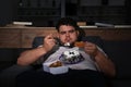 Depressed overweight man eating sweets in room at night Royalty Free Stock Photo