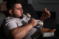 Depressed overweight man eating sweets in room at night Royalty Free Stock Photo