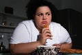 Depressed overweight woman eating sweets in kitchen Royalty Free Stock Photo