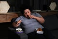 Depressed overweight woman eating sweets in room at night Royalty Free Stock Photo