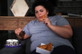 Depressed overweight woman eating sweets in room at night Royalty Free Stock Photo