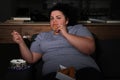 Depressed overweight woman eating sweets in room at night Royalty Free Stock Photo