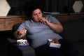 Depressed overweight woman eating sweets in room at night Royalty Free Stock Photo