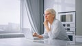 Depressed pensioner businesswoman types on grey laptop sitting at home