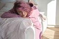 Depressed pensive teen girl introvert pink hair lying on bed looking away. Royalty Free Stock Photo