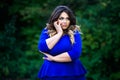 Depressed plus size fashion model in blue dress outdoors, beauty woman with professional makeup and hairstyle