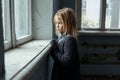 Depressed poot girl standing near window