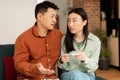 Depressed sad asian husband and wife upset of negative pregnancy test result, sitting on sofa in living room interior Royalty Free Stock Photo