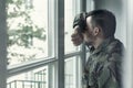 Depressed and sad soldier in green uniform with trauma after war standing near the window Royalty Free Stock Photo