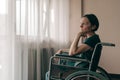 Depressed sad woman in worn wheelchair looking out the window Royalty Free Stock Photo