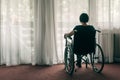 Depressed sad woman in worn wheelchair looking out the window Royalty Free Stock Photo