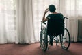 Depressed sad woman in worn wheelchair looking out the window Royalty Free Stock Photo