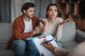 Depressed sad young european husband calm, support wife talking to psychologist in clinic interior Royalty Free Stock Photo
