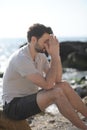 Depressed sad young man sitting on a sea beach Royalty Free Stock Photo