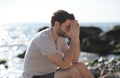 Depressed sad young man sitting on a sea beach Royalty Free Stock Photo