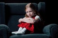 Depressed, scared child sitting in armchair and looking at camera