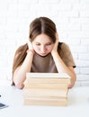 Depressed schoolgirl with a pile of books