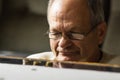 Depressed senior man in glasses sitting at the table and counting coins in a period of crisis. Pensioner poverty concept