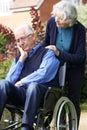 Depressed Senior Man In Wheelchair Being Pushed By Wife