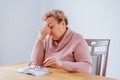 Depressed Senior Woman at Home Struggling with Eye Pain While Reading