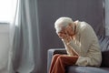 Depressed senior woman sitting on sofa