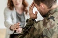 Depressed soldier with suicidal thoughts wearing green uniform during therapy with psychiatrist