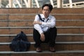 Depressed stressed young Asian business man in suit with hands on head sitting on stairs. Unemployment and layoff concept Royalty Free Stock Photo