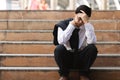 Depressed stressed young Asian business man in suit with hands on head sitting on stairs. Unemployment and layoff concept Royalty Free Stock Photo