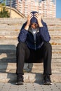 Depressed teenage boy holding his head with his hands sitting on stairs outdoors. Teen depression concept Royalty Free Stock Photo