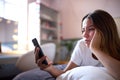 Depressed Teenage Girl Lying On Bed At Home Looking At Mobile Phone Royalty Free Stock Photo