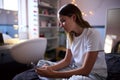 Depressed Teenage Girl Sitting On Bed At Home Looking At Mobile Phone Royalty Free Stock Photo