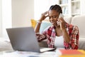 Depressed upset african female sit at workplace, using computer, phone Royalty Free Stock Photo