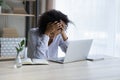 Depressed upset black female sit at workplace hug head