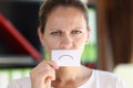 Depressed woman hides her mouth with white paper with sad sign. Royalty Free Stock Photo