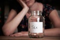 Depressed Woman Looking At Empty Jar Labelled Tax