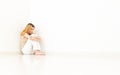 Depressed woman sitting in the corner of the room. The walls are Royalty Free Stock Photo