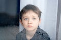 Depressed 7 years boy child looking out the window. Royalty Free Stock Photo