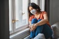 Depressed Young Arab Woman Wearing Protective Mask Sitting Near Windor At Home Royalty Free Stock Photo